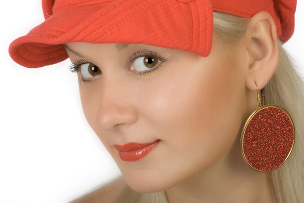 Όμορφη ξανθιά σε μια κόκκινη ΚΑΠ και κόκκινο σκουλαρίκια - Φωτογραφία, εικόνα