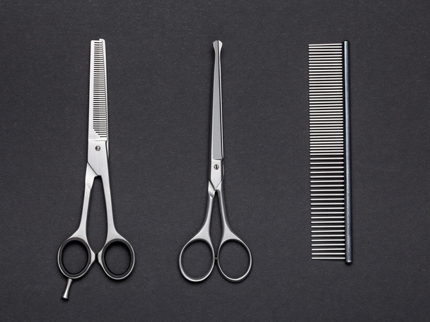 Two scissors and a metal comb on the black background - Photo, Image