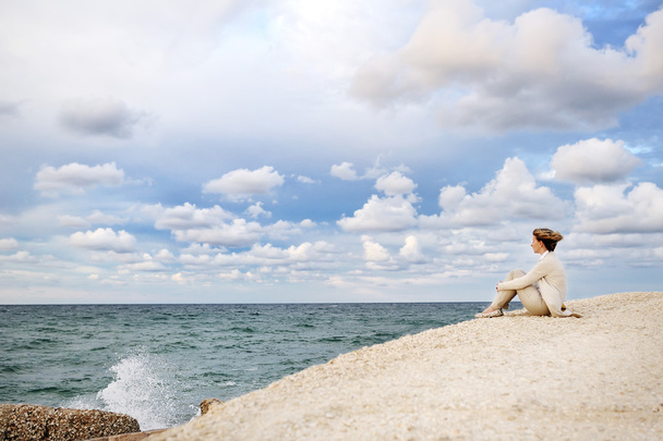 海と空を見て、ビーチに座っていた若い女性 - 写真・画像