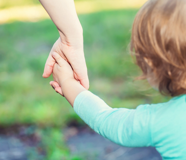 Toddler girl holding hands with her parent  - Foto, Imagen