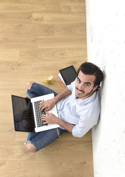 Nuori mies hipster moderni rento tyyli näyttää istuu olohuoneessa kotikerroksessa työskentelee kannettavan tietokoneen
  - Valokuva, kuva