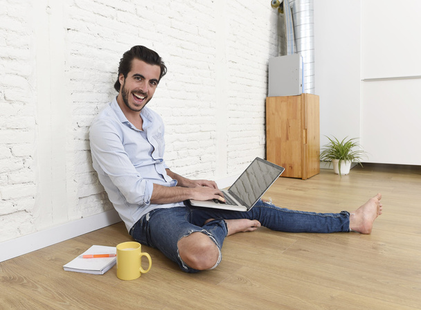 hombre joven en hipster moderno estilo casual mirada sentado en la sala de estar piso de casa trabajando en el ordenador portátil
  - Foto, imagen