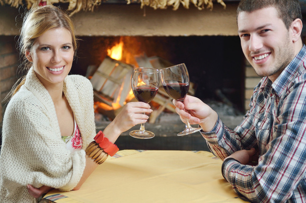 Young romantic couple sitting and relaxing in front of fireplace at home - Foto, imagen