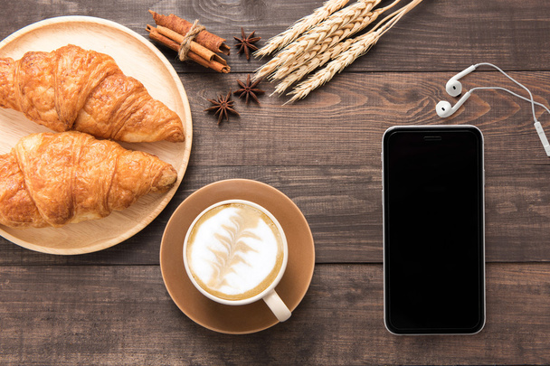 Coffee cup and fresh baked croissants on wooden background. Top  - Foto, imagen