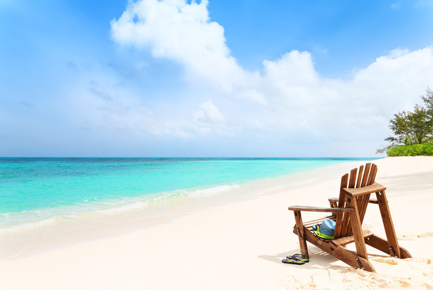 Самотній пляжний стілець з капелюхом і тапочками на тропічному пляжі, сума
 - Фото, зображення