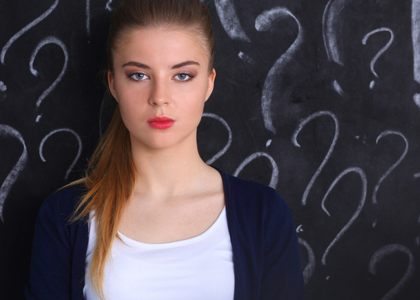 junges Mädchen mit Fragezeichen auf grauem Hintergrund - Foto, Bild