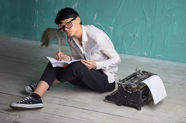 Jovem mulher de negócios trabalhando com documentos no chão, máquina de escrever retro
 - Foto, Imagem