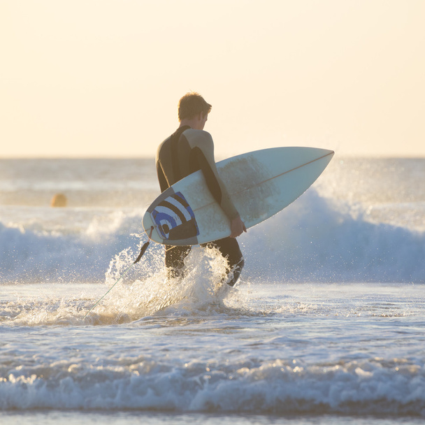 Silhouette eines Surfers am Strand mit Surfbrett. - Foto, Bild