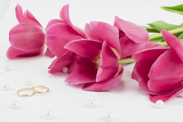 red tulips, wedding rings, perfume and bead - Foto, imagen