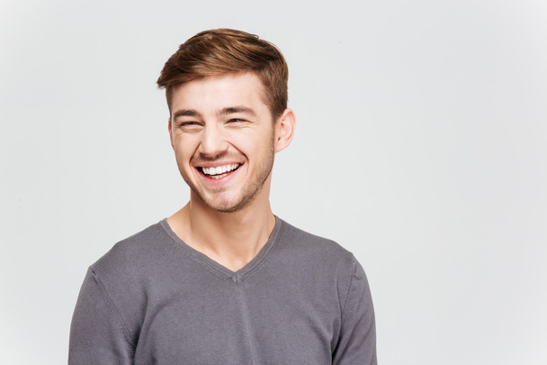 Cheerful attrative young man in grey pullover - Фото, изображение