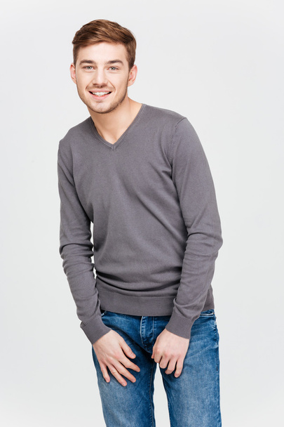 Smiling attractive young man in grey pullover and jeans - Photo, Image