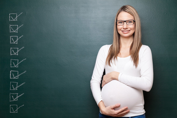 Pregnant woman and a blackboard with copyspace - Foto, imagen