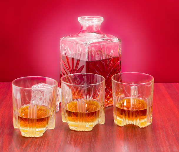 Decantador y tres vasos con whisky sobre una mesa de madera
 - Foto, Imagen