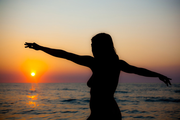 Mulher nua silhueta ao pôr do sol na praia
 - Foto, Imagem