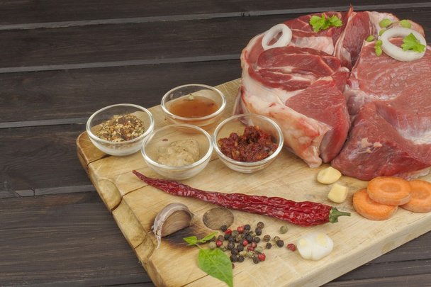 Specerijen en rauw rundvlees schacht op de snijplank. Voorbereiding van pittig eten. Decoratie voor het menu. Rundvlees klaar voor koken. - Foto, afbeelding
