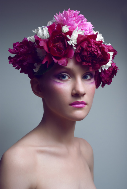 Studio portrait of young woman with peony in head - Foto, afbeelding