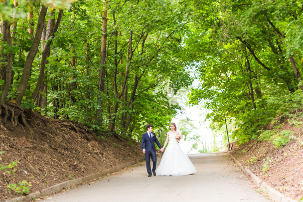 gelukkige bruid en bruidegom in een park op hun trouwdag - Foto, afbeelding