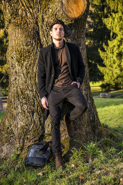 Handsome young man leaning against tree - Fotografie, Obrázek