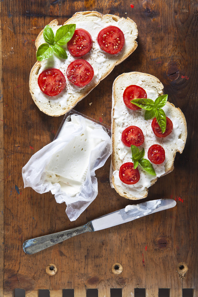 Bruschetta with soft cheese, basil and cherry tomatoes on a wood - Foto, Bild