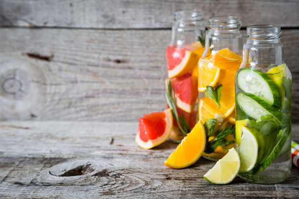 Selection of infused water in glass bottles, rustic wood background - Fotoğraf, Görsel