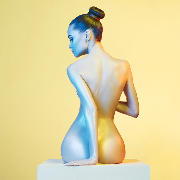 Elegant nude model in the light colored spotlights - Foto, afbeelding