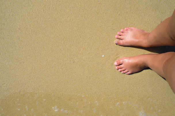 Κύματα της θάλασσας και τα πόδια κορίτσι καλοκαίρι άμμο της παραλίας. Κάτοψη - Φωτογραφία, εικόνα