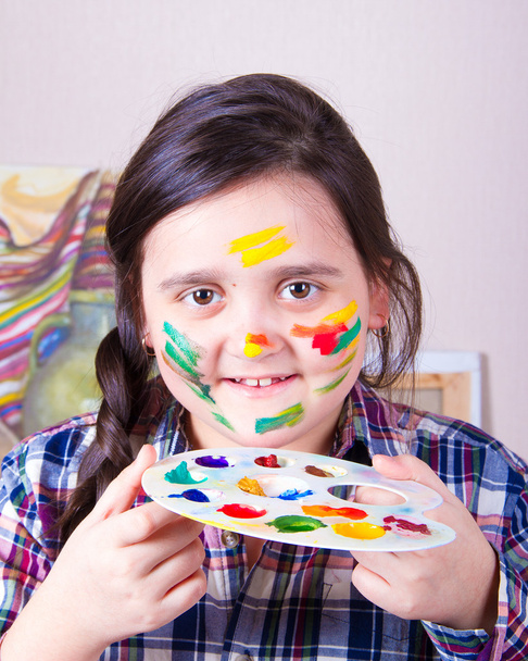 Ragazza con un viso macchiato in possesso di una tavolozza con colori e sorriso
 - Foto, immagini