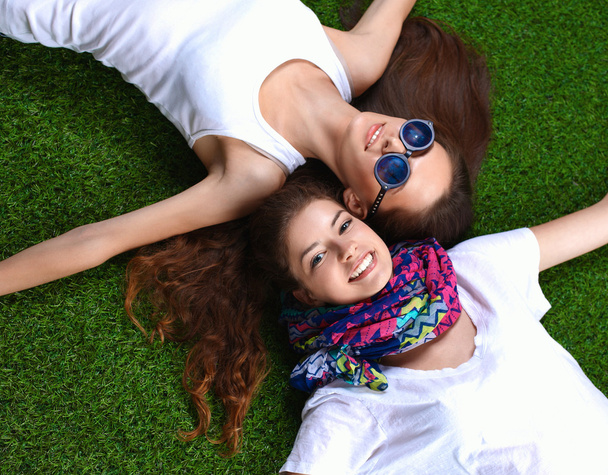 Kaksi nättiä tyttöä makaa tuoreella vihreällä ruoholla - Valokuva, kuva