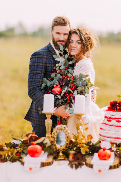 Happy wedding couple smiling at the holiday table. Field background - Foto, Imagen