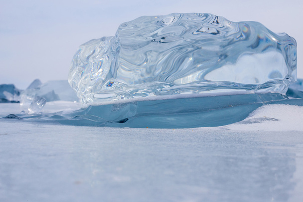 A transparent piece of ice on the surface of the blue frozen Lake Baikal. Blue transparent ice.  Lying on the ice. - Photo, image