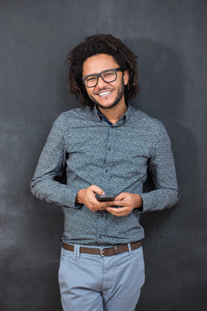 Typing message. Handsome young man with afro hair in shirt holdi - 写真・画像