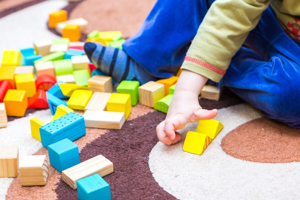 Small child playing with wooden blocks - 写真・画像