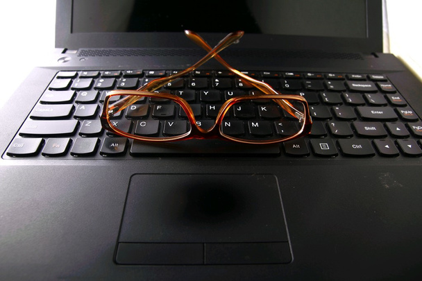 Par de óculos em um teclado de computador
 - Foto, Imagem