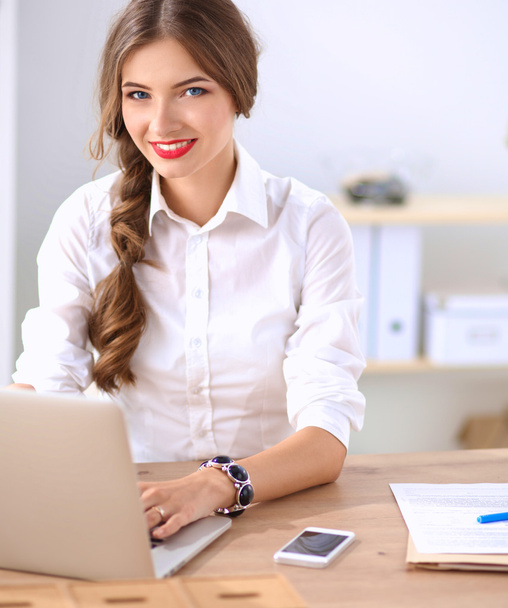 Attractive businesswoman sitting  on desk in the office - Фото, зображення