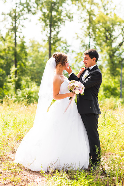 O noivo e a noiva num parque. Buquê de casamento nupcial de flores
 - Foto, Imagem
