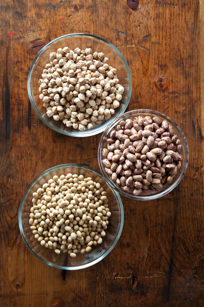 Bowls of various legumes (soybeans, chickpeas, beans) on wooden  - Photo, image