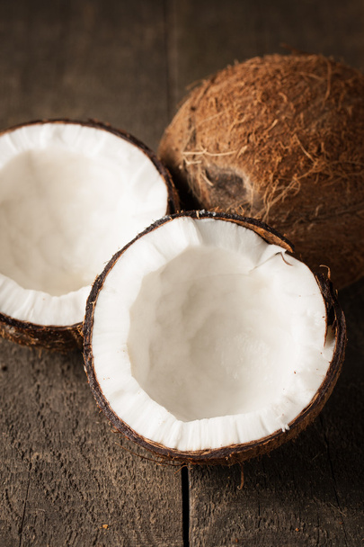 Ripe half cut coconut on a wooden background. Ripe half cut coconut with milk on a wooden background - Foto, imagen