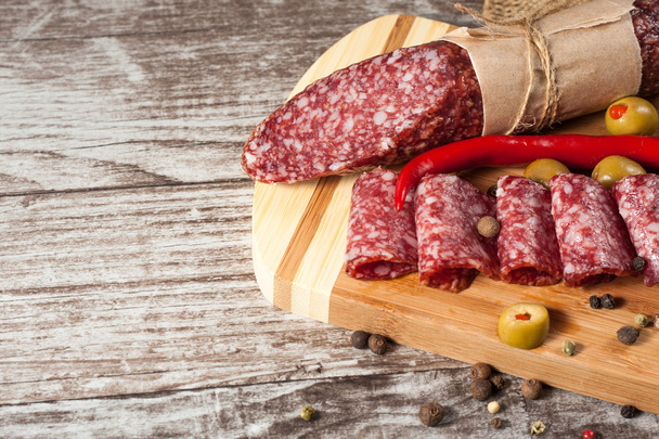 Italian salami with olives and spices on wooden background - Foto, Imagen