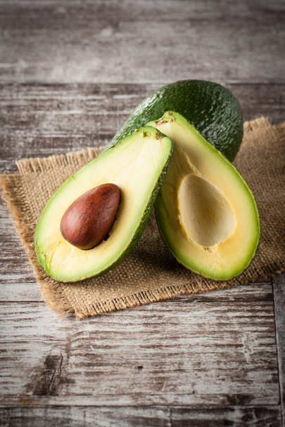 Nahaufnahme einer Avocado und Avocadoöl auf einem Holztisch. gesundes Ernährungskonzept. - Foto, Bild