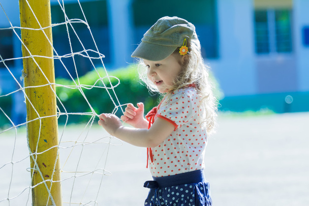 Przedszkole dziewczyna gra w pobliżu piłka nożna cel netto z bramki żółty - Zdjęcie, obraz
