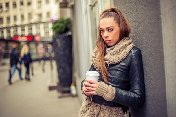 Kaunis nainen juo kahvia kadulla.
 - Valokuva, kuva