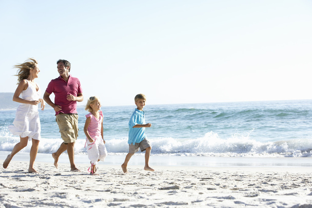 Family Running Along Sandy Beach - 写真・画像