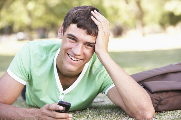 Ευτυχισμένος φοιτητής με το κινητό στο πάρκο - Φωτογραφία, εικόνα