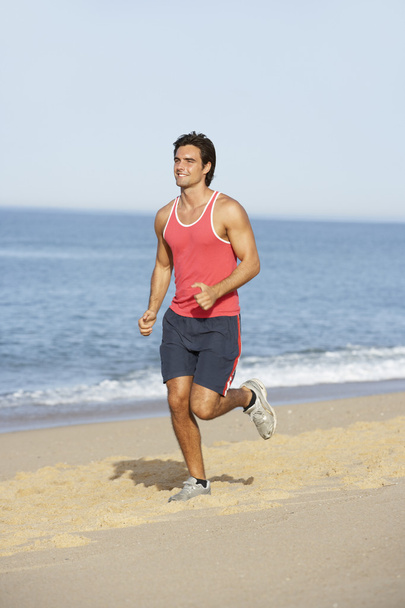 Young Man Jogging Along Beach - Фото, изображение