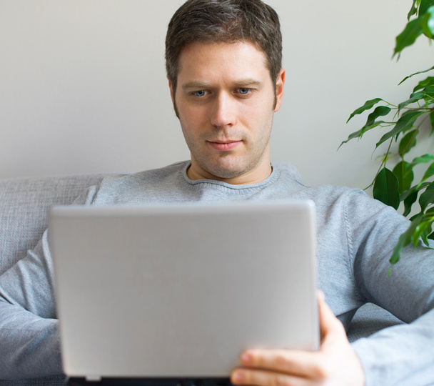 Hombre relajante con ordenador portátil en el sofá
. - Foto, imagen