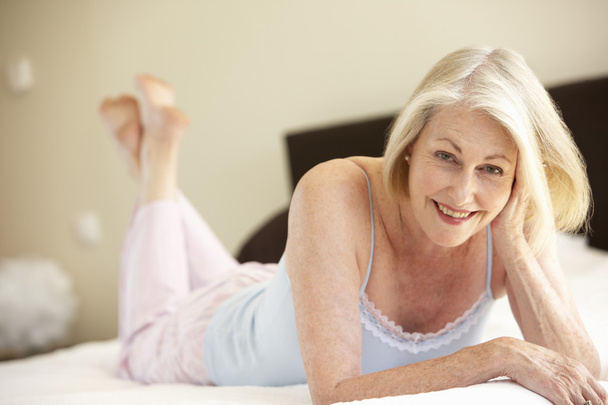 Senior Woman Relaxing On Bed - Foto, imagen