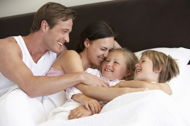 Young Family Having Fun In Bed - Фото, зображення