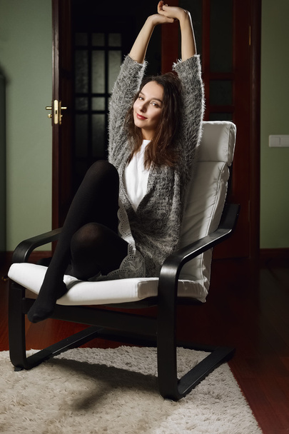 charming young girl stretching herself sitting in armchair - Фото, изображение