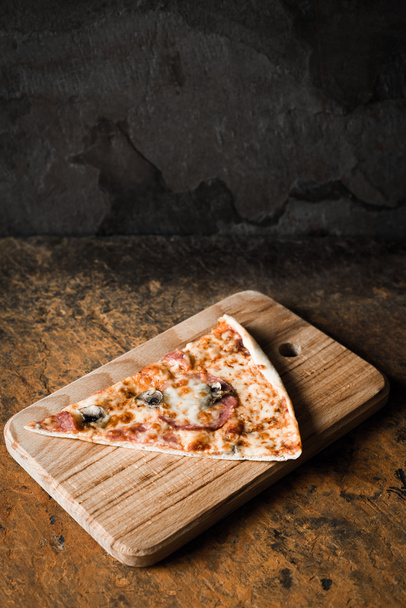 Plak van pizza op het houten bord verticale - Foto, afbeelding