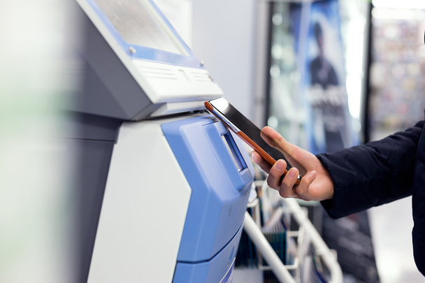 Frau bezahlt am Fahrkartenautomaten per Handy - Foto, Bild